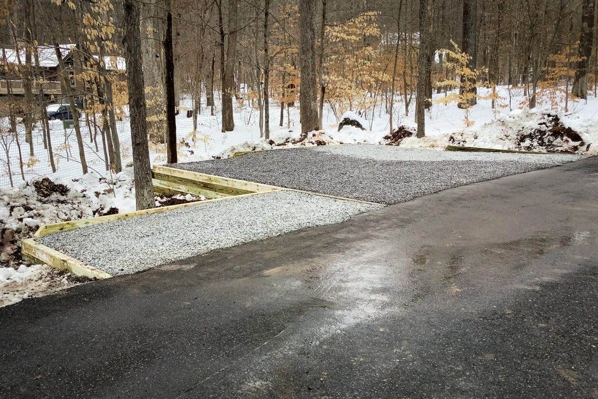 A gravel parking pad with lumber retaining walls