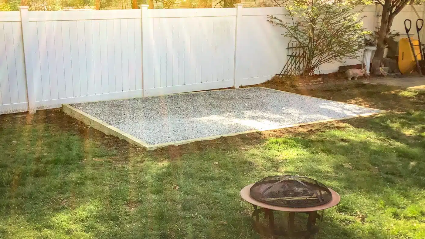 A fire pit gravel patio beside a privacy fence