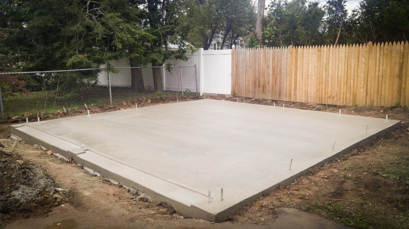 Concrete pad shed footing with anchors