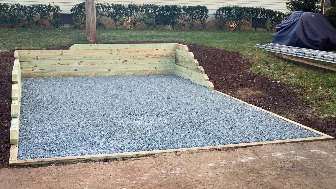 A shed foundation made from gravel and pressure-treated lumber on a sloped site