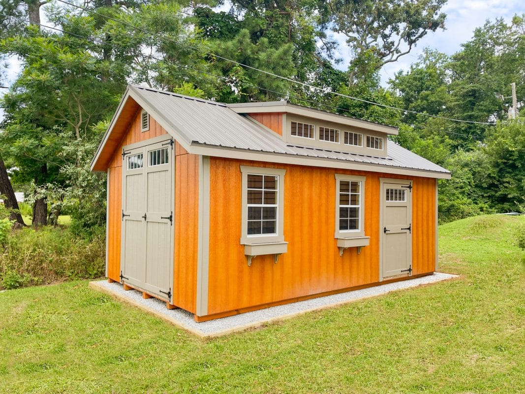 exterior of an orange shed on a gravel shed foundation