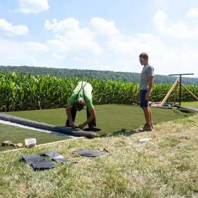 two men working outside working on an artificial grass installation